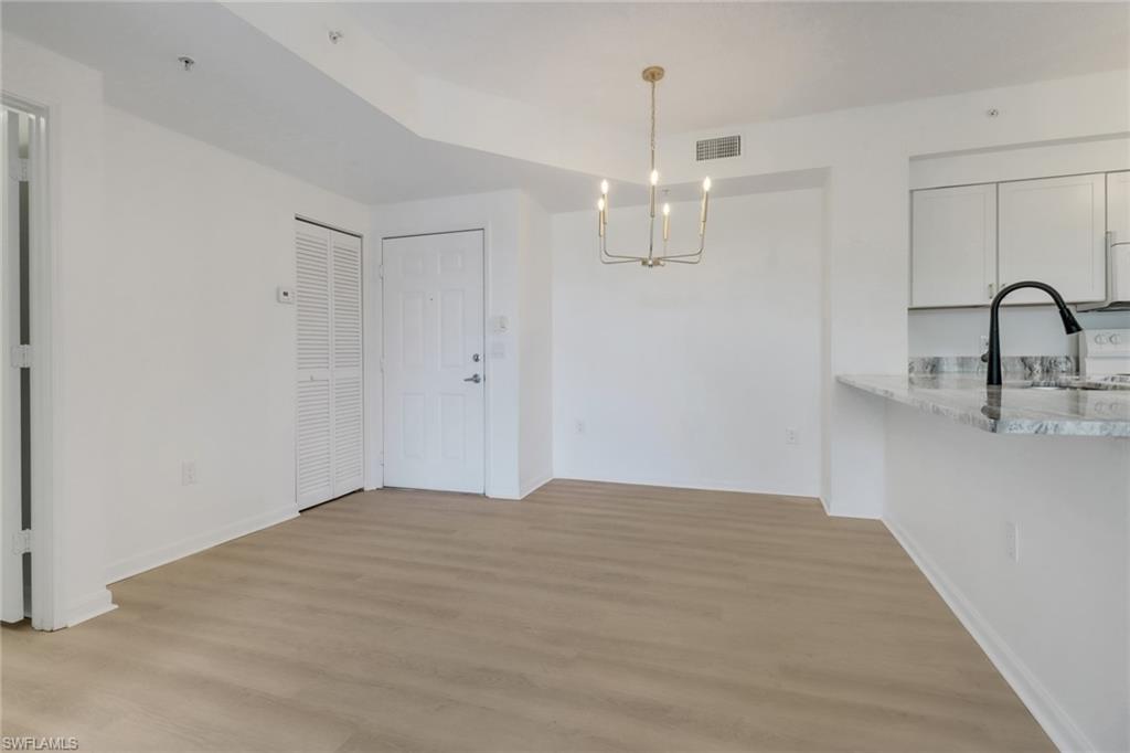 1190 Reserve Way, Unit 206 Naples, FL 34105 - Photo 7 of 35 a view of an empty room with wooden floor and kitchen