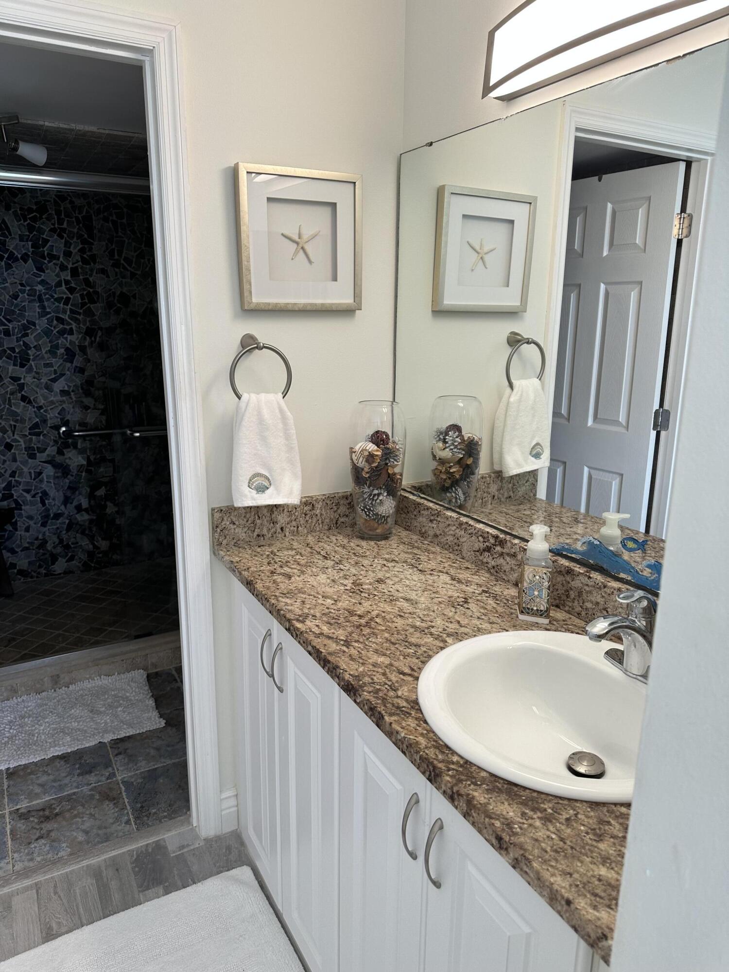 7370 South Ocean Drive, Unit 215 Jensen Beach, FL 34957 - Photo 17 of 51 a bathroom with a granite countertop sink a mirror and shower