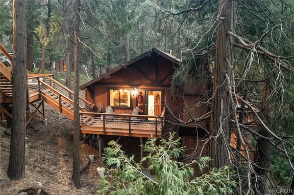 a view of a house with a small yard and large trees