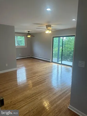 a view of empty room with wooden floor and fan