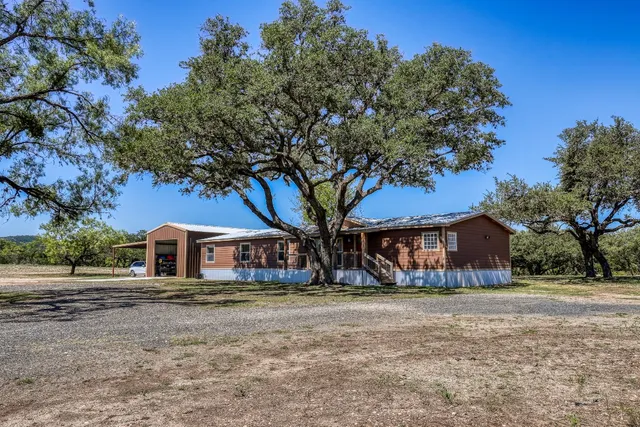 a front view of a house with large trees