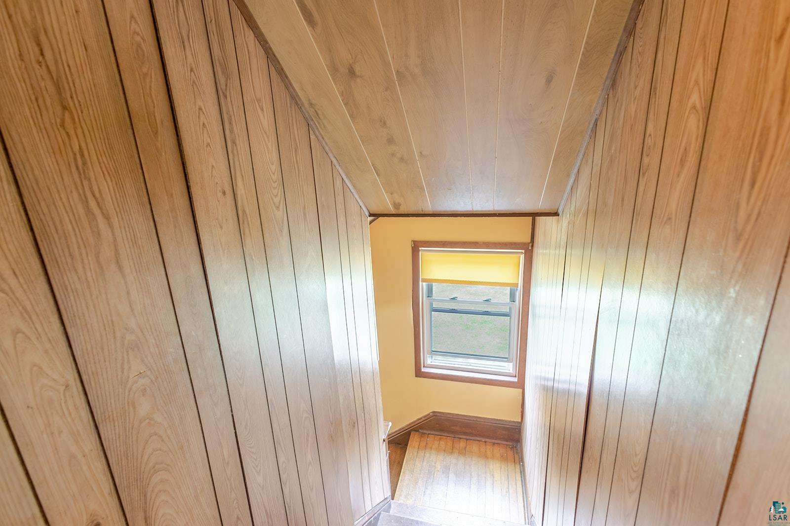438 9th Street Cloquet, MN 55720 - Photo 16 of 27 Stairwell featuring wood-finish paneling, a double-hung window, and wood-finish flooring