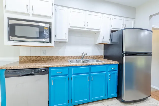a kitchen with granite countertop a refrigerator and a stove top oven