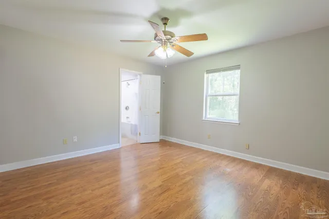an empty room with wooden floor chandelier fan and windows
