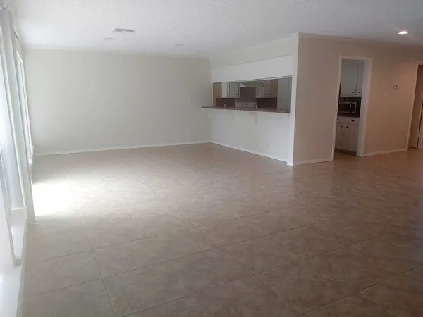 an empty room with windows and refrigerator
