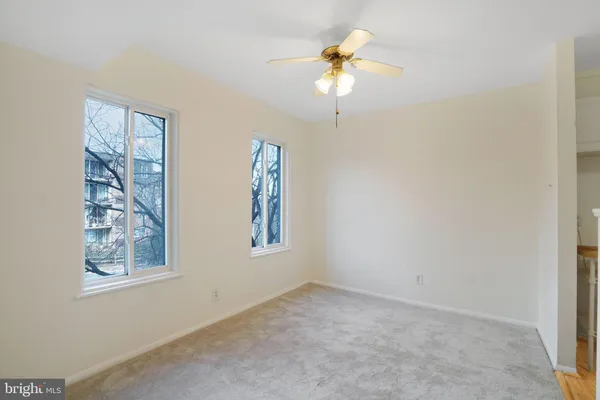 an empty room with windows and chandelier fan