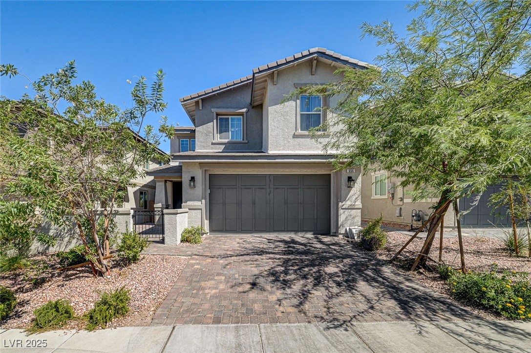 View of front facade featuring a gate, decorative driveway, stucco siding, and an attached garage