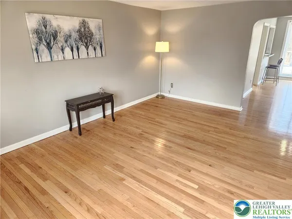 a view of a room with wooden floor and paintings on the wall