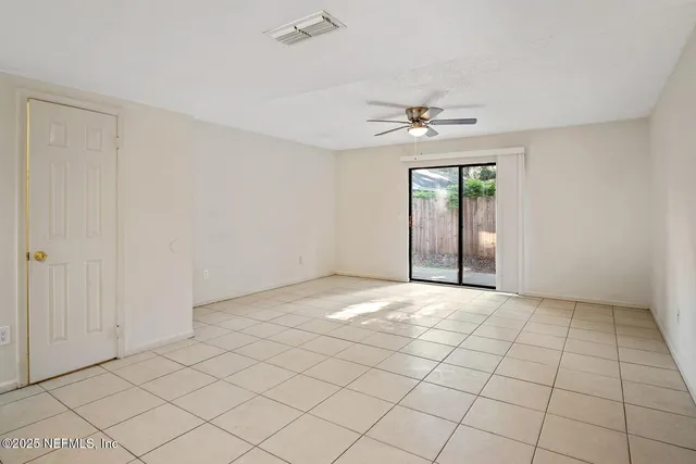 an empty room with windows and fan chandelier