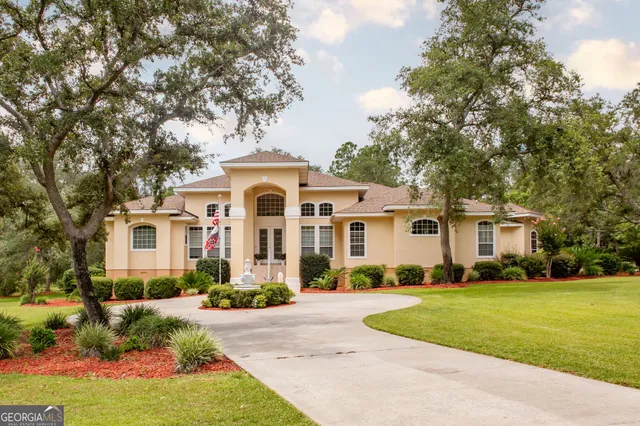 a front view of a house with a garden and trees