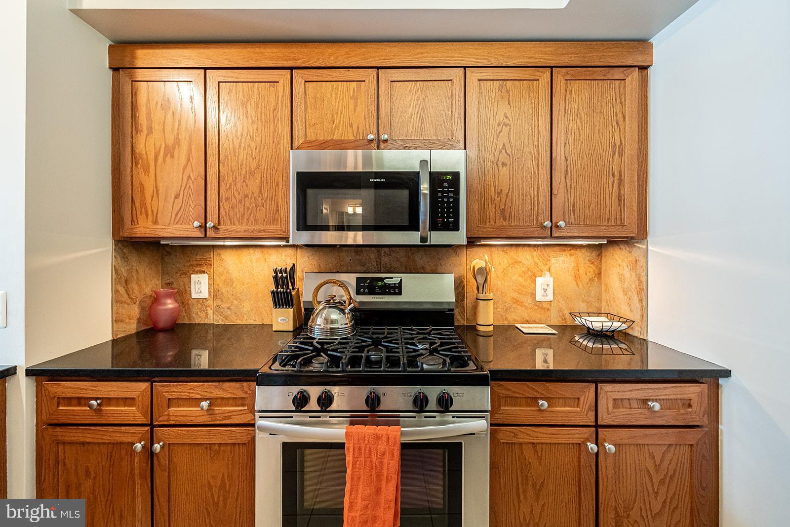631 D Street Northwest, Unit 1231 Washington, DC 20004 - Photo 7 of 34 a kitchen with granite countertop wooden cabinets and a stove top oven