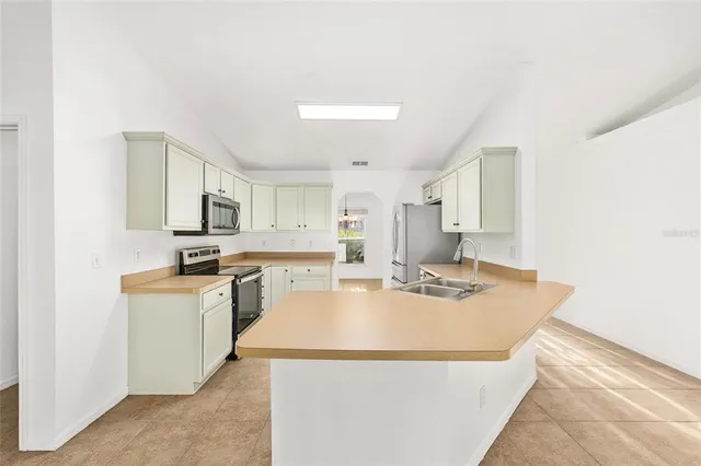 a kitchen with kitchen island a stove a sink a refrigerator a counter top space and cabinets