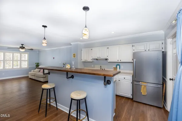 a kitchen with stainless steel appliances granite countertop a refrigerator a sink dishwasher a stove and a dining table with wooden floor