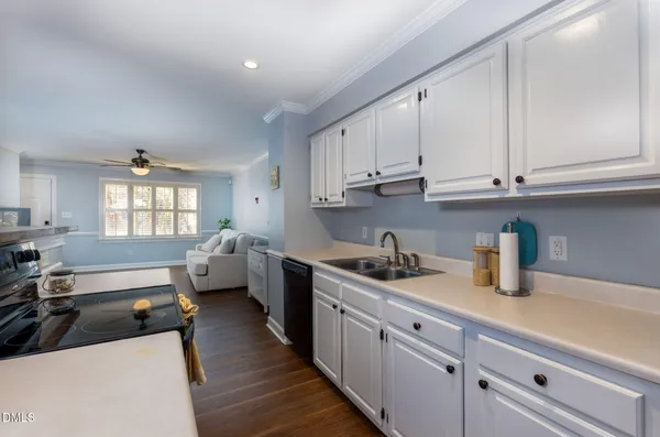 a kitchen with a sink dishwasher stove and white cabinets