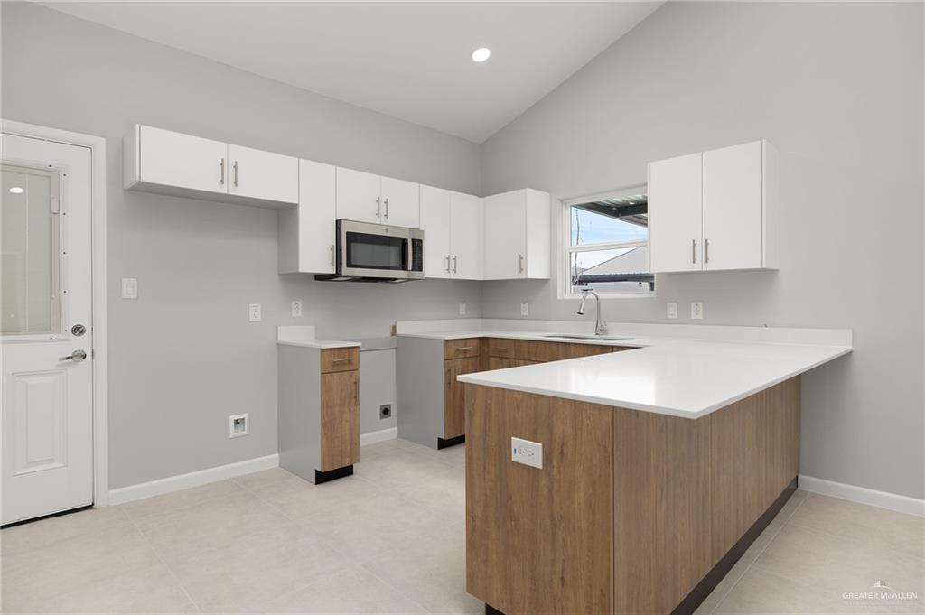 2701 Robin Road Weslaco, TX 78596 - Photo 7 of 30 a kitchen with a sink a stove a microwave and white cabinets
