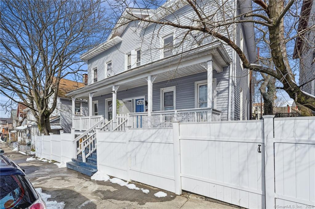a view of a white house with a large tree