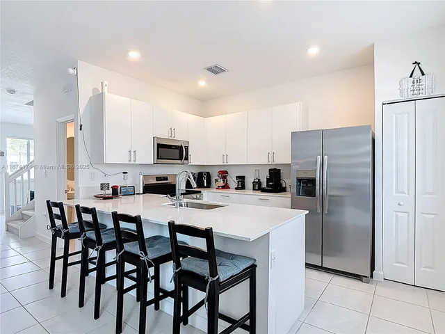 a kitchen with stainless steel appliances a refrigerator sink and white cabinets