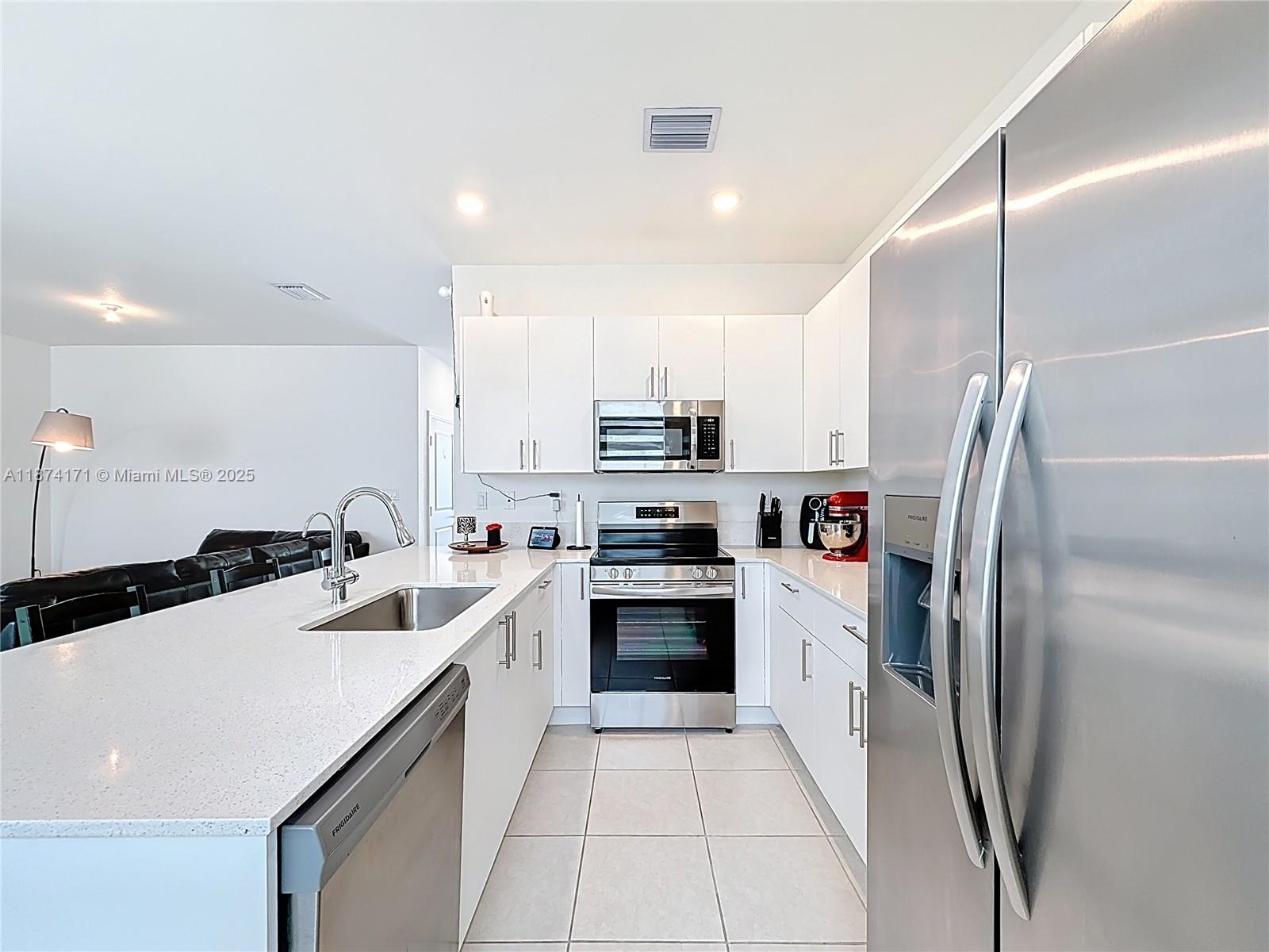716 Southeast 14th Street Homestead, FL 33034 - Photo 24 of 60 a kitchen with stainless steel appliances a refrigerator sink and white cabinets