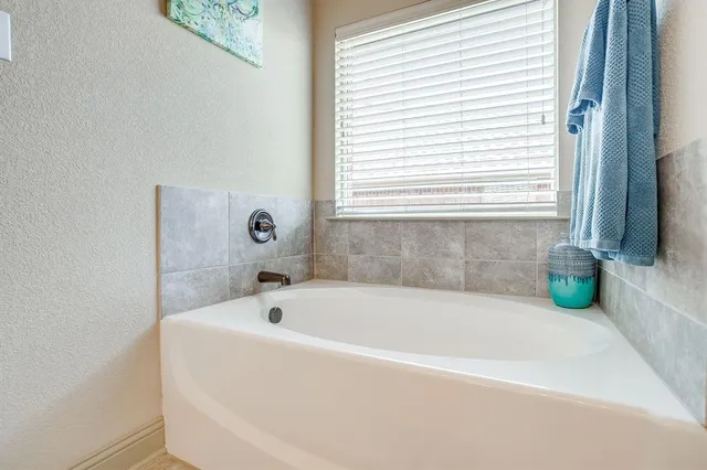 a white bath tub sitting in a bathroom next to a window
