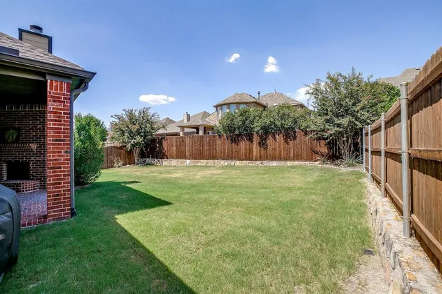 a backyard of a house with plants and wooden fence