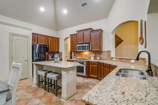 a kitchen with stainless steel appliances granite countertop a stove a sink a oven a dining table and chairs