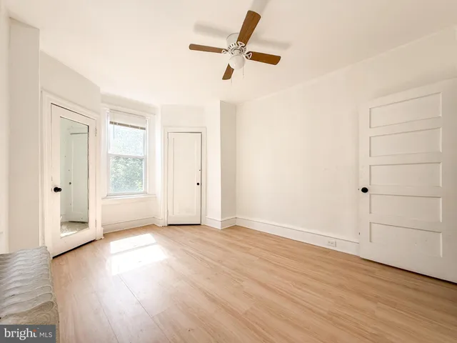an empty room with wooden floor fan and windows
