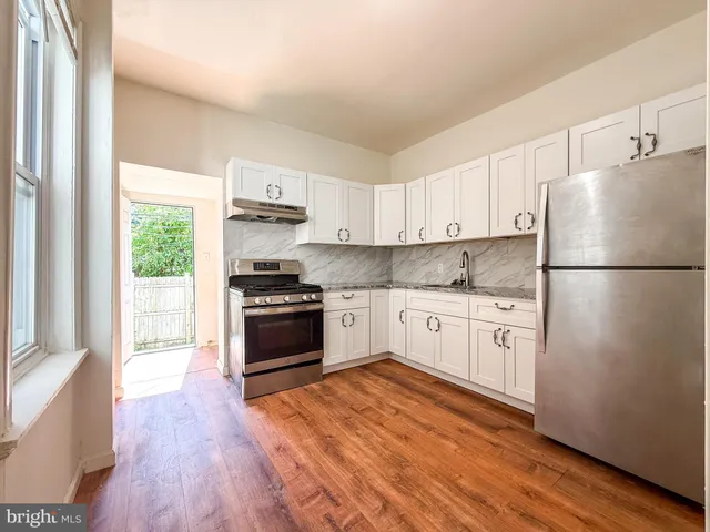 a kitchen with granite countertop a refrigerator stove top oven and sink