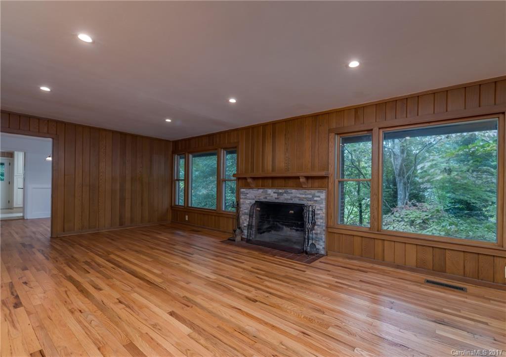 81 Jericho Drive Tryon, NC 28782 - Photo 10 of 23 an empty room with wooden floor fireplace cabinet and windows