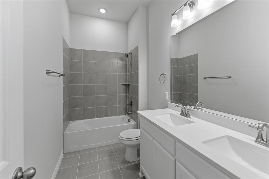 104 Snowy Owl Trail Rhome, TX 76078 - Photo 17 of 27 Dual sink vanity with white cabinetry and integrated countertops