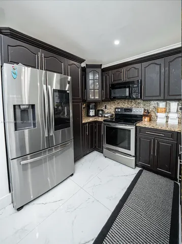 a kitchen with stainless steel appliances granite countertop a stove top oven and refrigerator