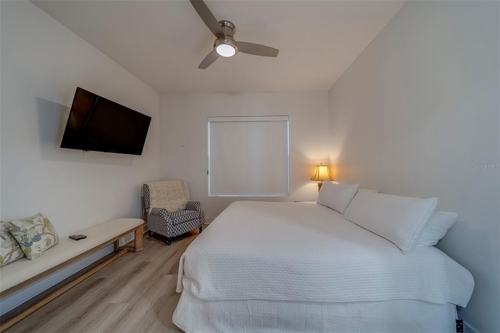 400 150th Avenue, Unit 407 Madeira Beach, FL 33708 - Photo 24 of 59 a bedroom with a bed and a flat screen tv