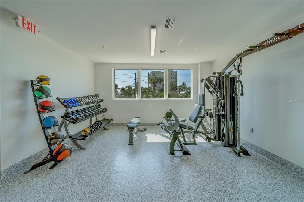 400 150th Avenue, Unit 407 Madeira Beach, FL 33708 - Photo 44 of 59 a living room with furniture gym equipment and a chandelier