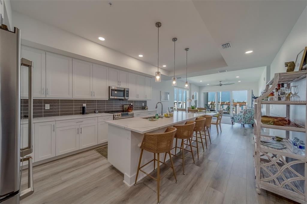 400 150th Avenue, Unit 407 Madeira Beach, FL 33708 - Photo 6 of 59 a kitchen with stainless steel appliances kitchen island granite countertop a table chairs refrigerator and microwave