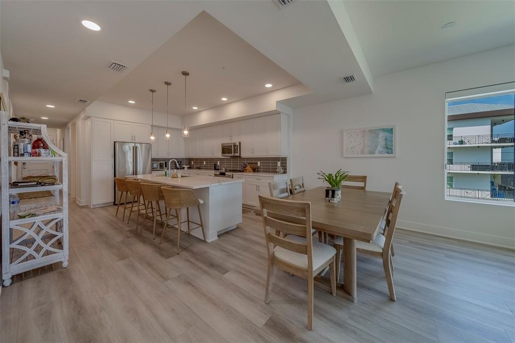 400 150th Avenue, Unit 407 Madeira Beach, FL 33708 - Photo 9 of 59 a kitchen with stainless steel appliances a dining table chairs and wooden floor