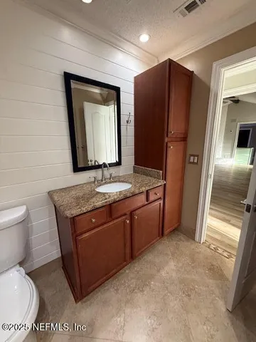 a bathroom with a granite countertop toilet sink and mirror