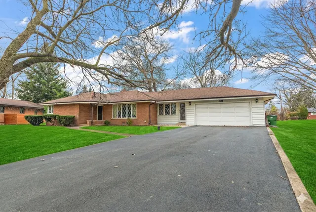 a view of a house with a yard and large tree