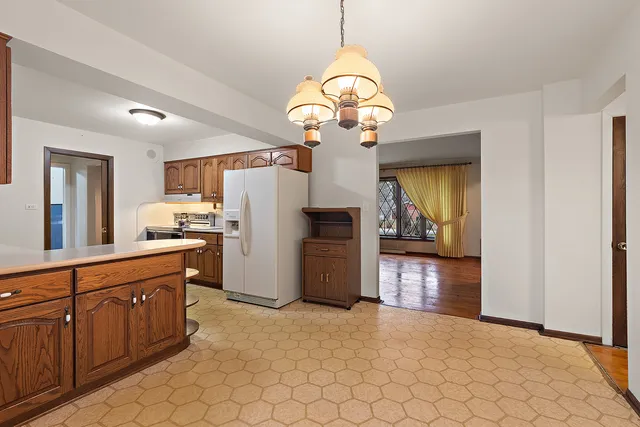 a kitchen that has a lot of cabinets stainless steel appliances and a chandelier