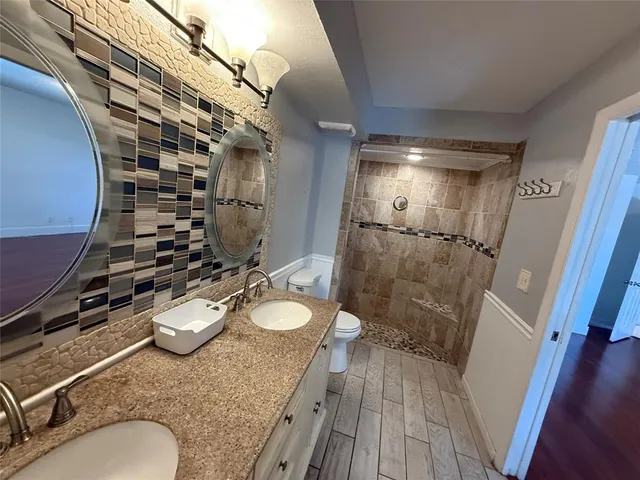 a bathroom with a granite countertop sink a toilet and shower