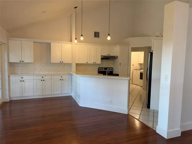 a view of a kitchen with wooden floor and electronic appliances