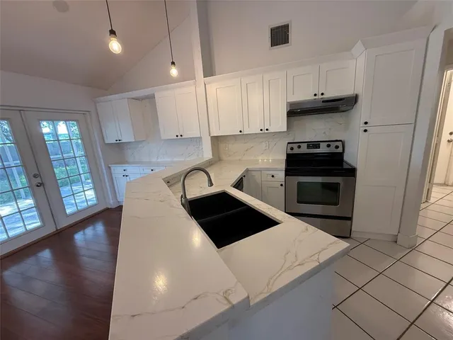 a kitchen with granite countertop a stove a sink and a refrigerator