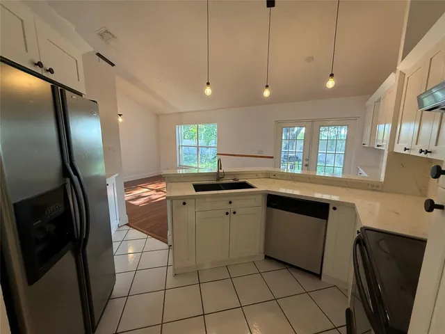 a kitchen with granite countertop a sink a counter space and stainless steel appliances