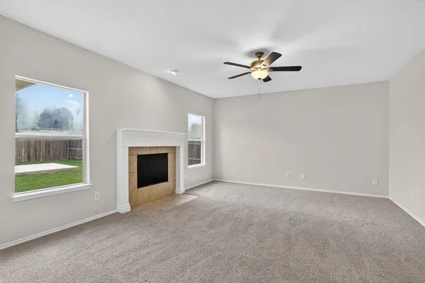 an empty room with chandelier fan and windows