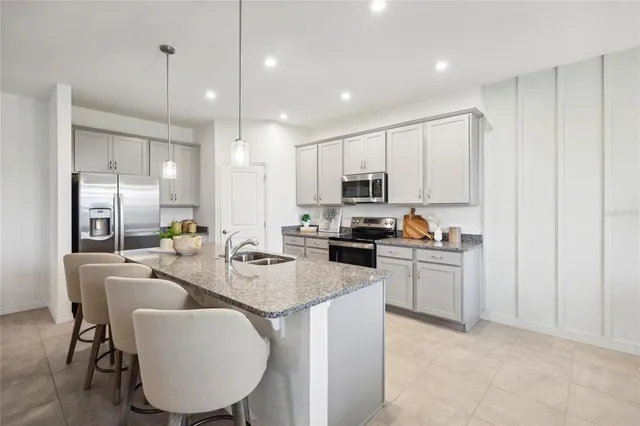 a kitchen with kitchen island granite countertop a sink a counter space appliances and cabinets