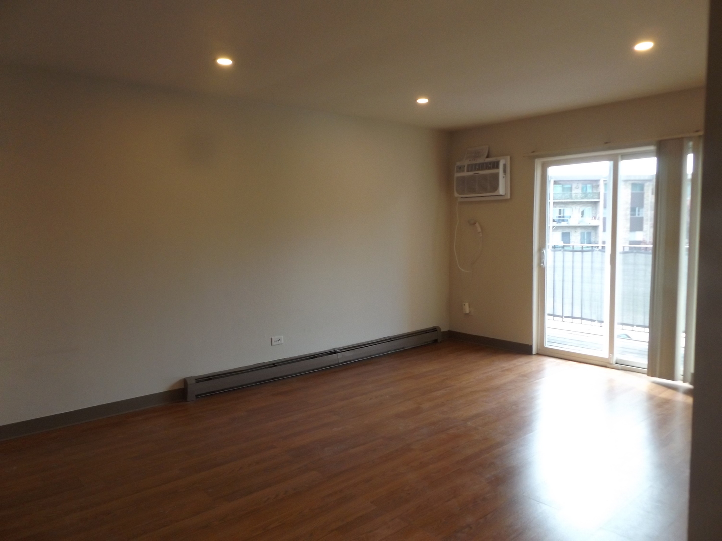 710 West Huntington Commons Road, Unit 3A Mount Prospect, IL 60056 - Photo 5 of 10 an empty room with wooden floor and windows with curtains