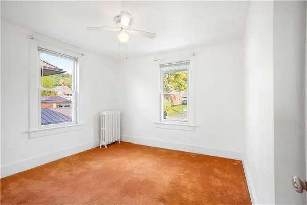 an empty room with windows and ceiling fan