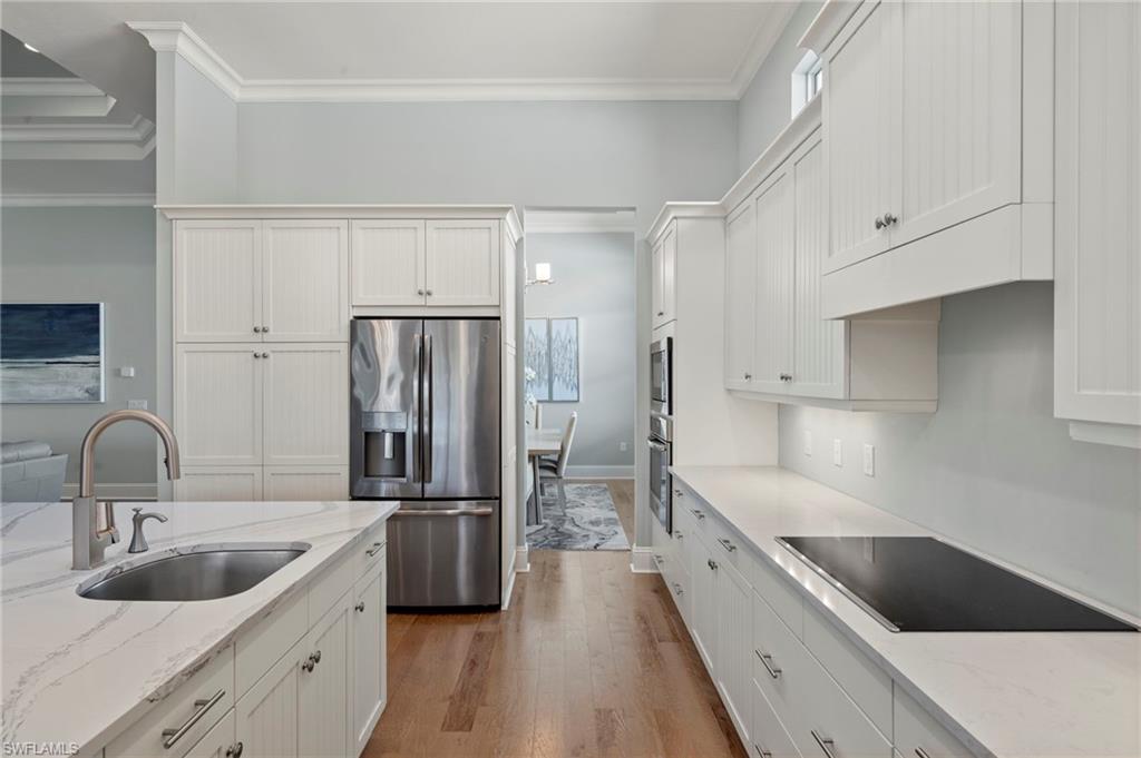 6420 Pembroke Way Naples, FL 34113 - Photo 22 of 39 Kitchen with light Quartz counters, white cabinetry, appliances with stainless steel finishes, View of Dining Room Entry