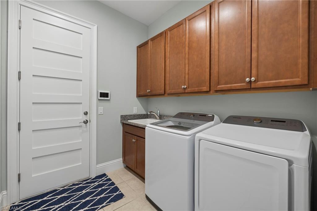 6420 Pembroke Way Naples, FL 34113 - Photo 25 of 39 Laundry area featuring cabinets, sink, light tile patterned floors, and washing machine and clothes dryer. Notice the 8' Shaker Doors