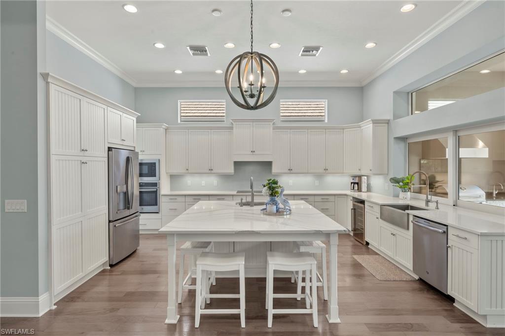 6420 Pembroke Way Naples, FL 34113 - Photo 6 of 39 Kitchen with a large quartz island with sink, stainless steel appliances, and crown molding