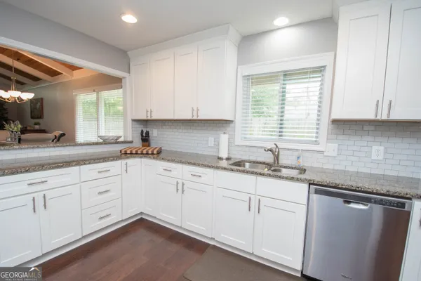 a kitchen with granite countertop white cabinets sink and window