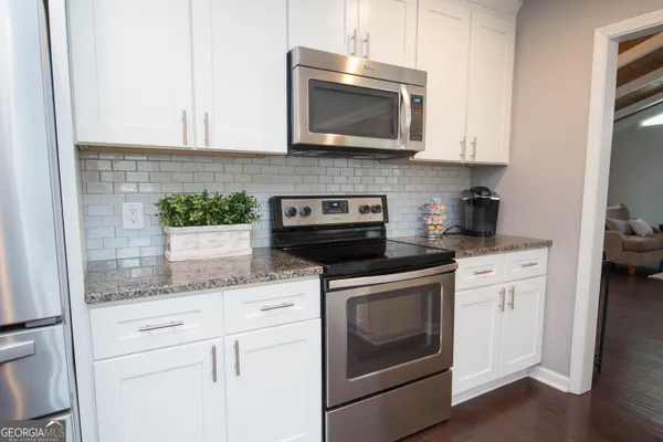 a kitchen with stainless steel appliances granite countertop white cabinets granite counter tops and a wooden floors